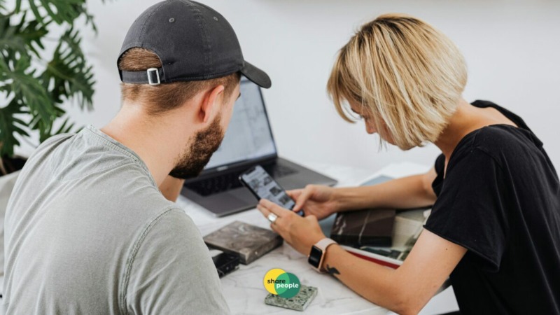 twee zzp'ers kijken samen op laptop en mobiel om te onderzoeken wat risico's zijn van geen AOV