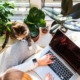zzp'er werkt op de laptop bij het raam met planten en kat