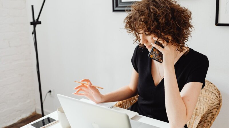 een freelancer die vragen stelt aan de telefoon voordat ze een AOV gaat afsluiten